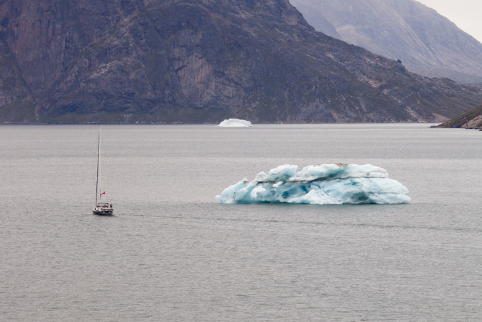 A sailing boat rounding an iceberg.